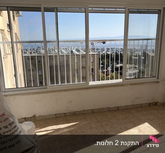ויטרינת חלונות הזזה מאלומיניום לבן שהותקנה במרפסת בדירה בשיפוץ
